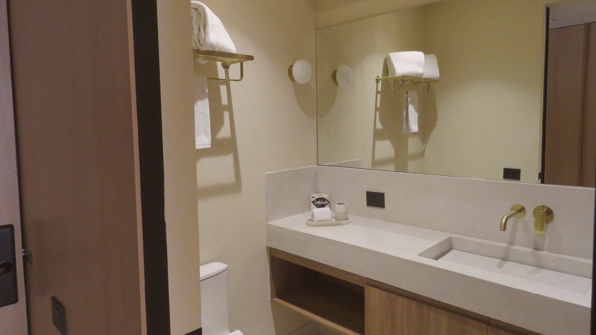 A bathroom with a white sink, a mirror, a towel rack, and a toilet.