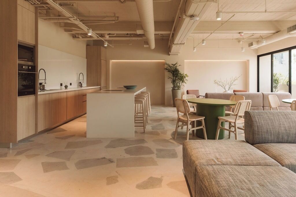 Una cocina moderna con una isla central, zona de comedor con sillas y un sofá.
