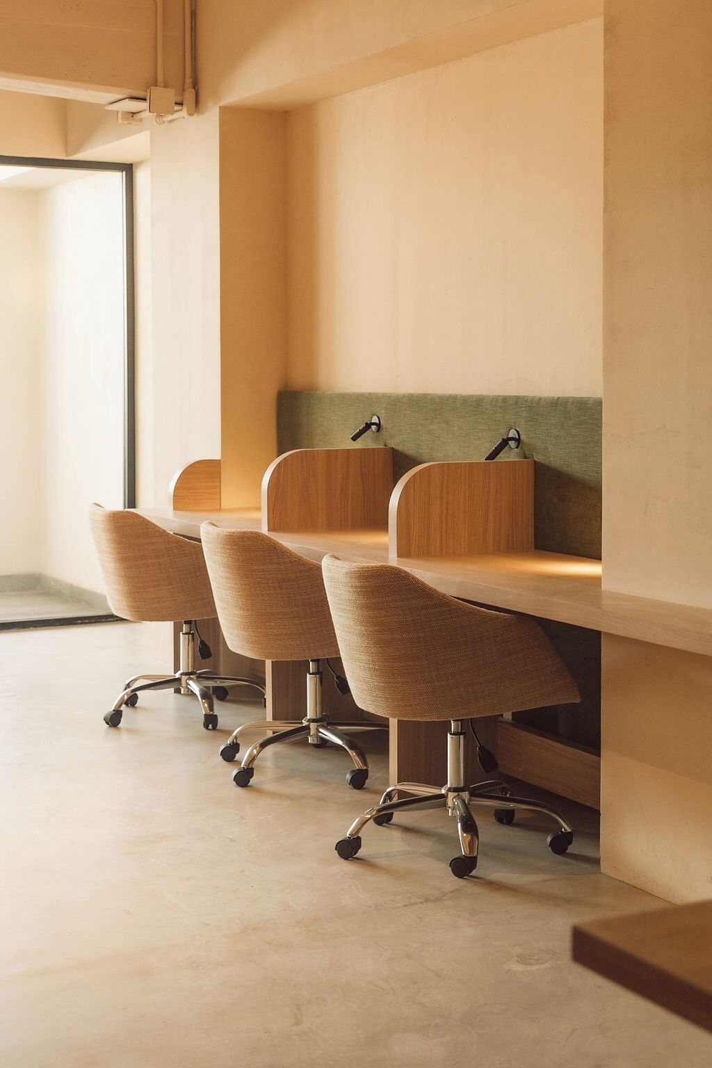 A conference room with four chairs and a table, featuring a light-colored floor and a green accent wall.