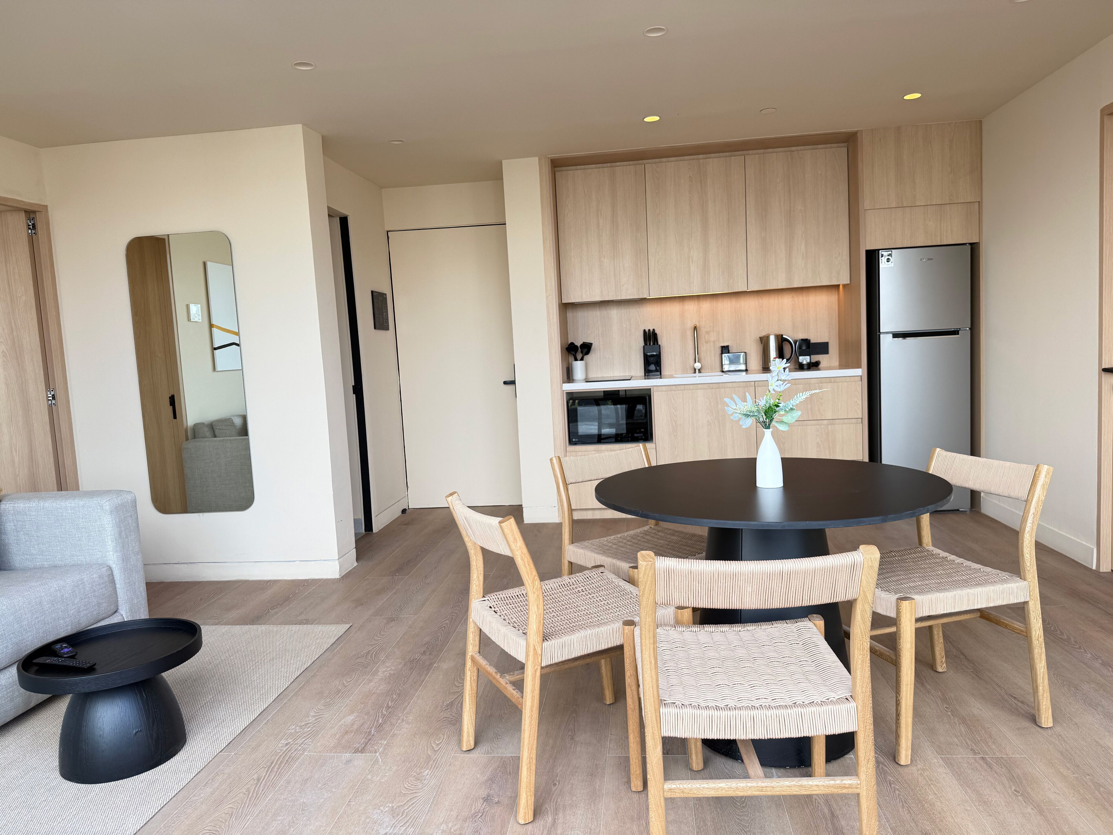 A modern kitchen with a dining area, including a round table, chairs, and a refrigerator.
