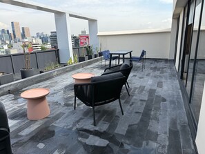 A rooftop terrace with a seating area, potted plants, and a city view. - Park Life Lamartine (Mexico City)