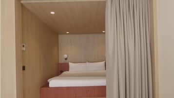 A hotel room with a wooden ceiling, a bed with white bedding, and a light-colored curtain.