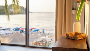 A view of a beach with umbrellas and boats, a wooden table with a woven basket and a vase with a plant. - Maramara Playa Beach Hotel (Sayulita)