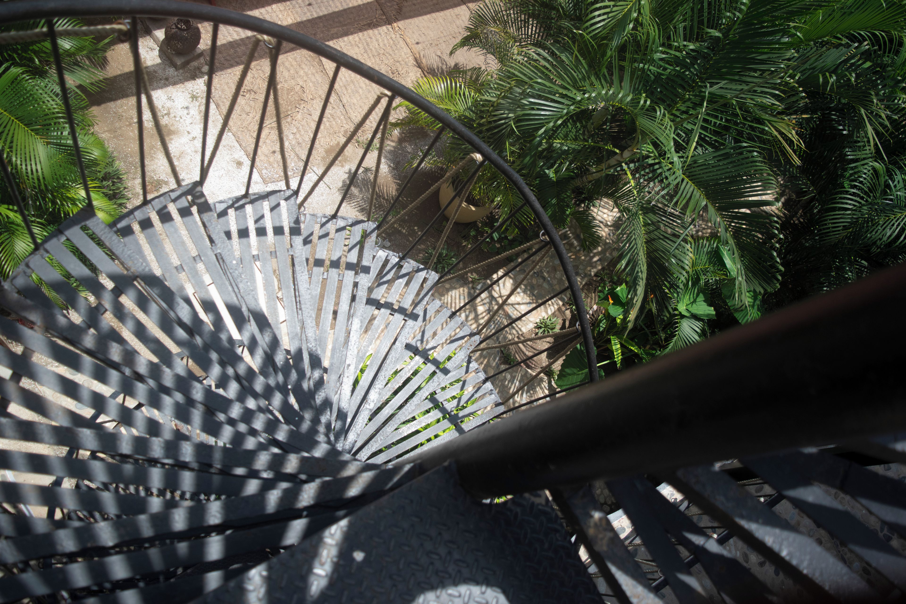 Una escalera de caracol con barandas de metal y vistas de la vegetación circundante.