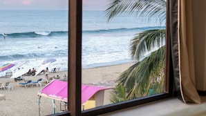 A view from a window overlooking a beach with umbrellas and palm trees. - Maramara Playa Beach Hotel (Sayulita)