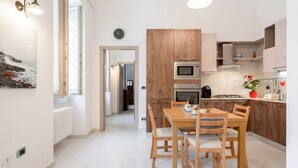 Eine moderne Küche mit Holzausstattung, einem Esstisch mit Stühlen und Blick auf den Flur.