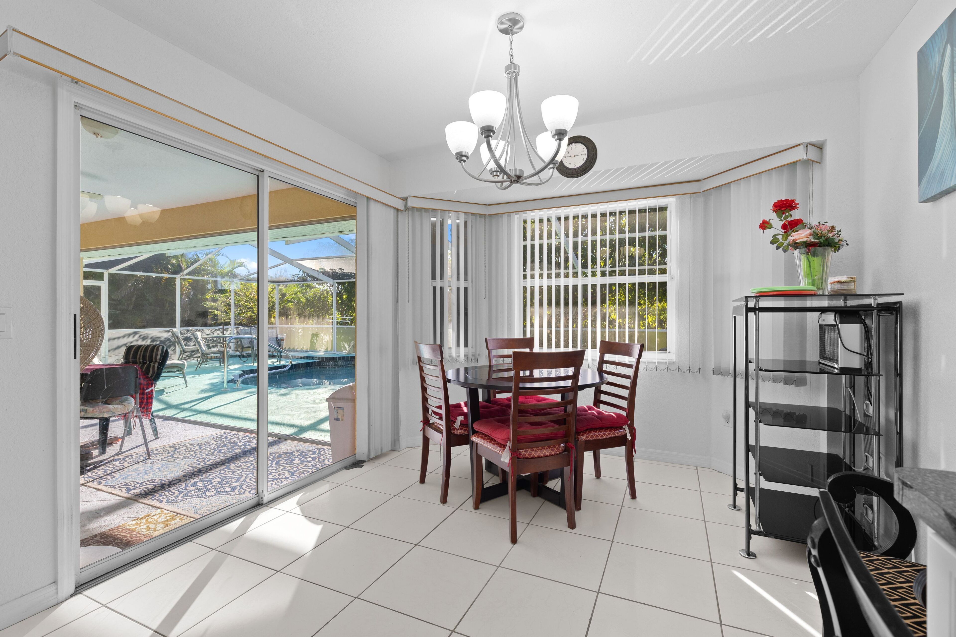 A dining area with a glass door leading to a pool, a chandelier, and a view of the outdoors.