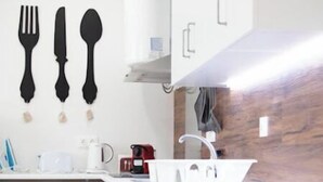 Eine moderne Küche mit weißen Schränken, einem Backofen, einer Spüle und einer Kaffeemaschine.