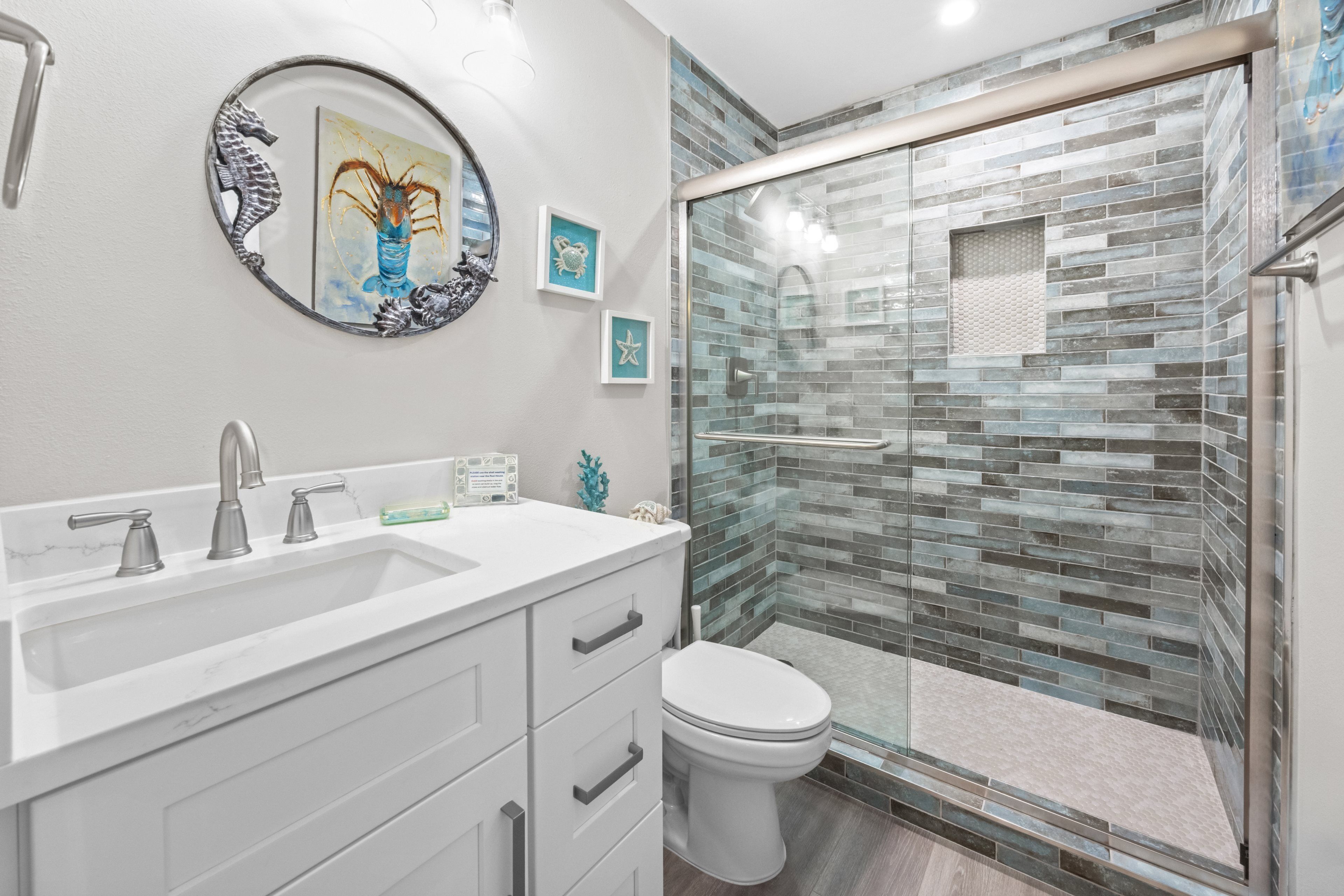 A bathroom with a white vanity, a glass shower enclosure, and a toilet.