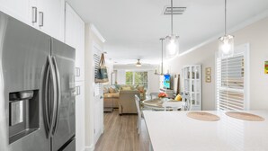A modern kitchen with stainless steel appliances, a white countertop, and a dining area with a white table and chairs.