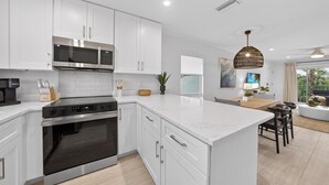 A modern kitchen with white cabinetry, stainless steel appliances, and a large island.