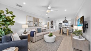 A modern living room with a sofa, coffee table, and a dining area with a table and chairs.