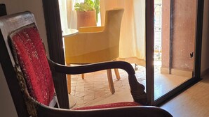 Una sedia con un cuscino rosso in una stanza con una porta a vetri scorrevoli che dà su uno spazio esterno con un tavolo e piante in vaso.