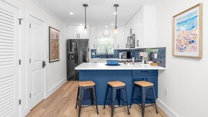Una cocina moderna con una isla central, taburetes de bar e iluminación colgante.