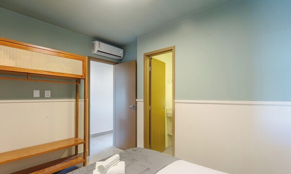 A room with a bunk bed, a door leading to a bathroom, and an air conditioning unit on the wall. - Your Exclusive Stay Just Steps From the sea - BBC (Maraú)