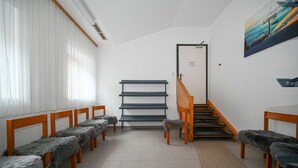 Une pièce avec des bancs en bois, un escalier et un tableau accroché au mur.