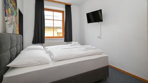 Ein Hotelzimmer mit Bett, Wandfernseher und einem Vorhangfenster.
