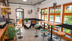 Ein modernes Interieur mit Bar, Sitzgelegenheiten und großen Fenstern mit Blick auf die Straße.