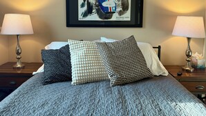 Ett hotellrum med en säng, kuddar, en inramad bild av en Formel 1-bil och två sänglampor.
