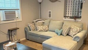 A living room with a sofa, ottoman, coffee table, and a lamp. - 4 Blocks to the Erie Beaches (Millcreek Township)
