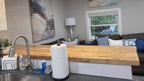 A modern kitchen with a wooden countertop, stainless steel sink, and pendant lights. - Coastal Comforts - Fire pit (Millcreek Township)
