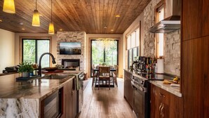 A modern kitchen with a large island, stone accents, wooden beams, and pendant lighting. - Pool w/ a grotto!/Hot Tub/Game Room/Rooftop Deck - Appalachian Falls (Sevierville)