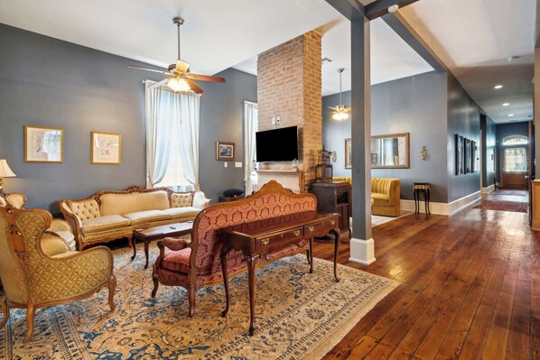 A spacious living room with a fireplace, a large sofa, a patterned rug, and a television mounted on the wall.