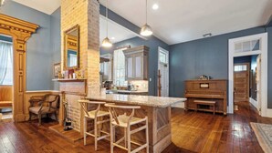 A spacious kitchen with a central island, wooden bar stools, and a large mirror above the island. - Victorian Villa w Heated Pool & Hot Tub 5BR|6BA (New Orleans)