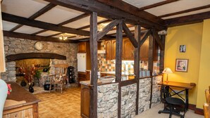 A rustic kitchen with stone walls, wooden beams, and a checkered tile backsplash. - Hall House Estate - 4 Properties- St Florence (Tenby)