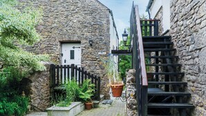 A narrow stone alley with a wooden staircase leading to a building with a white door and a sign that reads "The Inn." - Hall House Estate - 4 Properties- St Florence (Tenby)