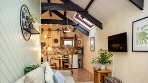A cozy living room with a sofa, a small table, and a window overlooking a kitchen. - Hall House Estate - 4 Properties- St Florence (Tenby)