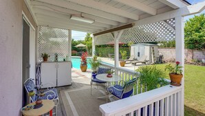 Ein überdachter Patio-Bereich mit Außenmöbeln, einem Pool und Topfpflanzen.