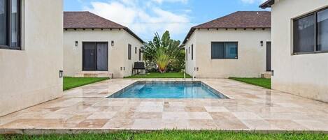 A modern building with a swimming pool, two-story structure, and a well-maintained lawn.