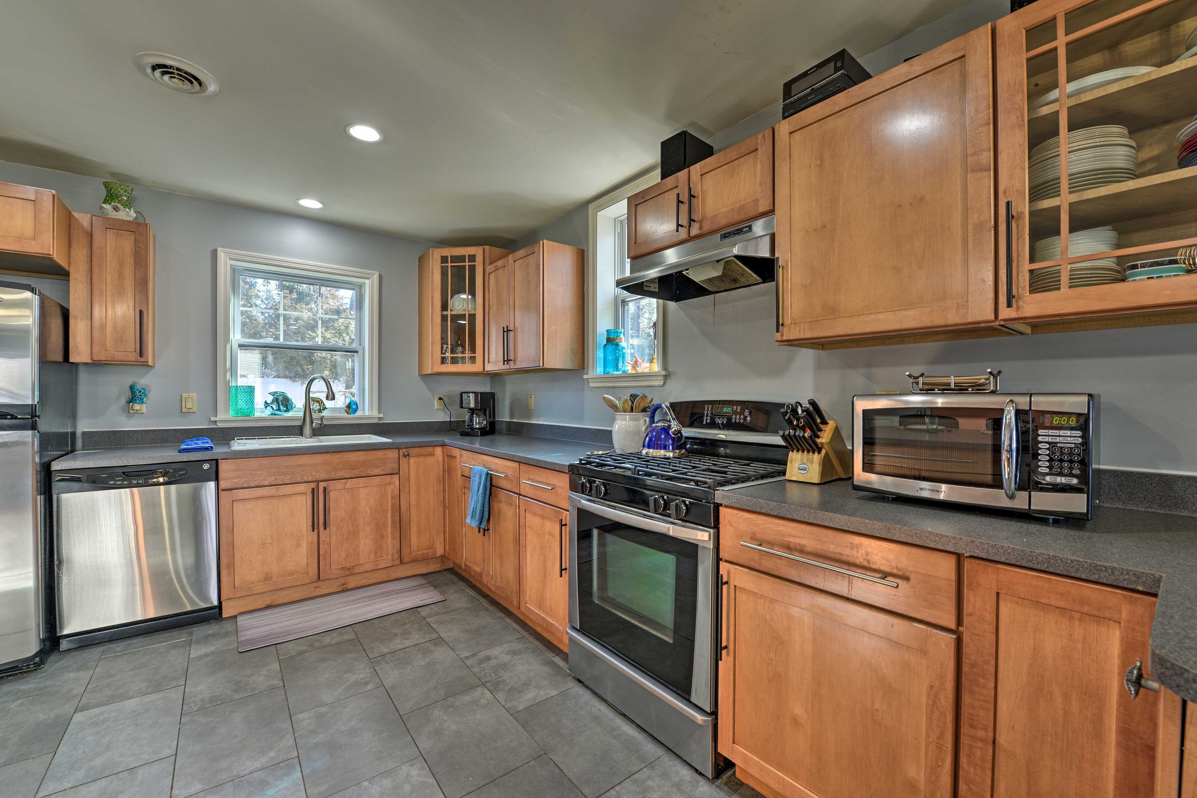 A modern kitchen with wooden cabinets, stainless steel appliances, and a window providing natural light.