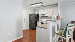 A compact kitchen with white cabinetry, a stainless steel refrigerator, a microwave, and a stove. - Southeast Crestview near I-10 (Crestview)
