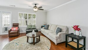 A living room with a brown leather sofa, a beige couch, a coffee table, and a side table with a vase of flowers. - Southeast Crestview near I-10 (Crestview)