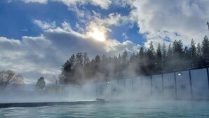 Un baño de vapor con vistas a un bosque y un cielo despejado.