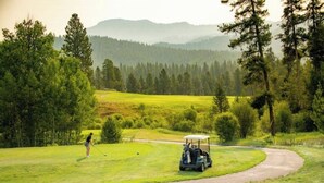 Un campo de golf con un carrito de golf y un golfista.