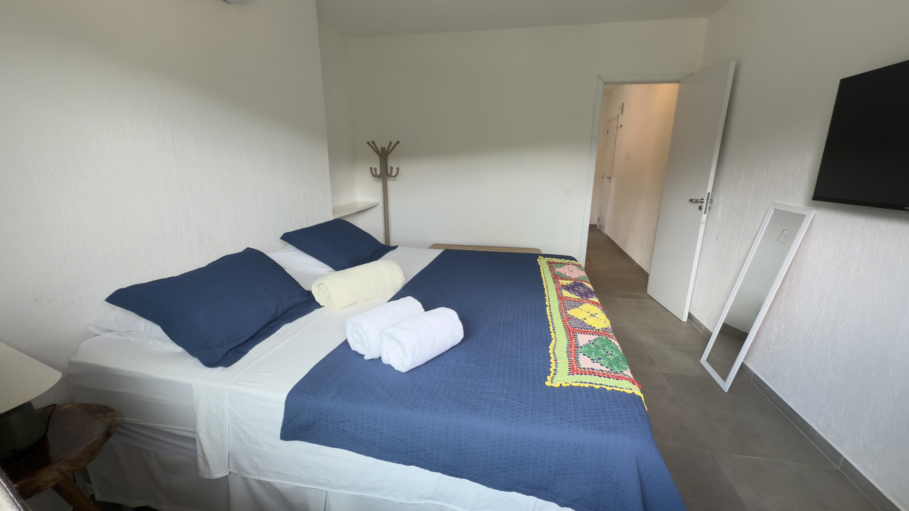 A hotel room with a bed, pillows, a blanket, and a towel.