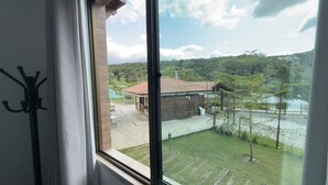 Vista desde una ventana que da a un edificio con tejado de tejas, un área verde y una masa de agua.