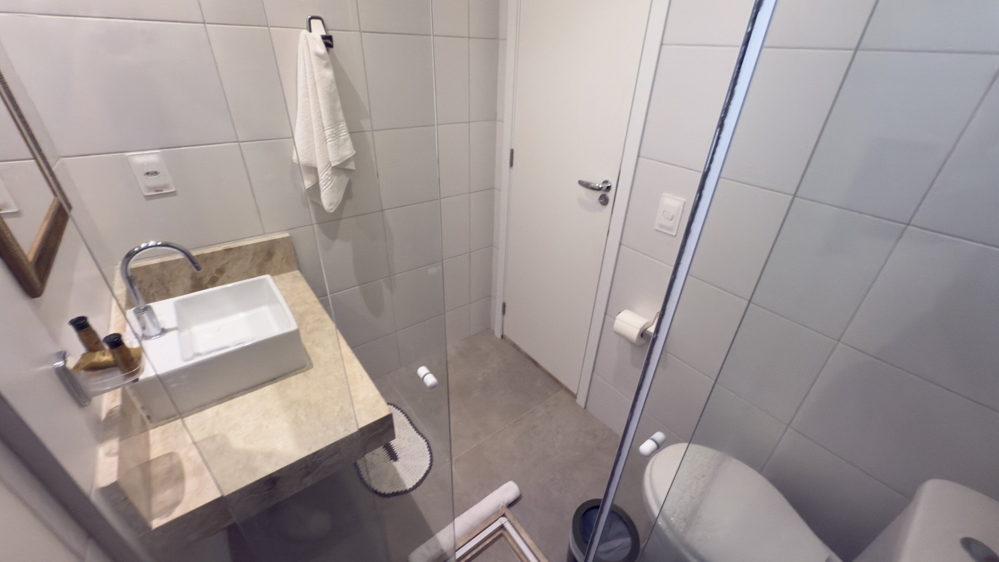 A modern bathroom with a glass shower enclosure, a white sink, and a toilet.