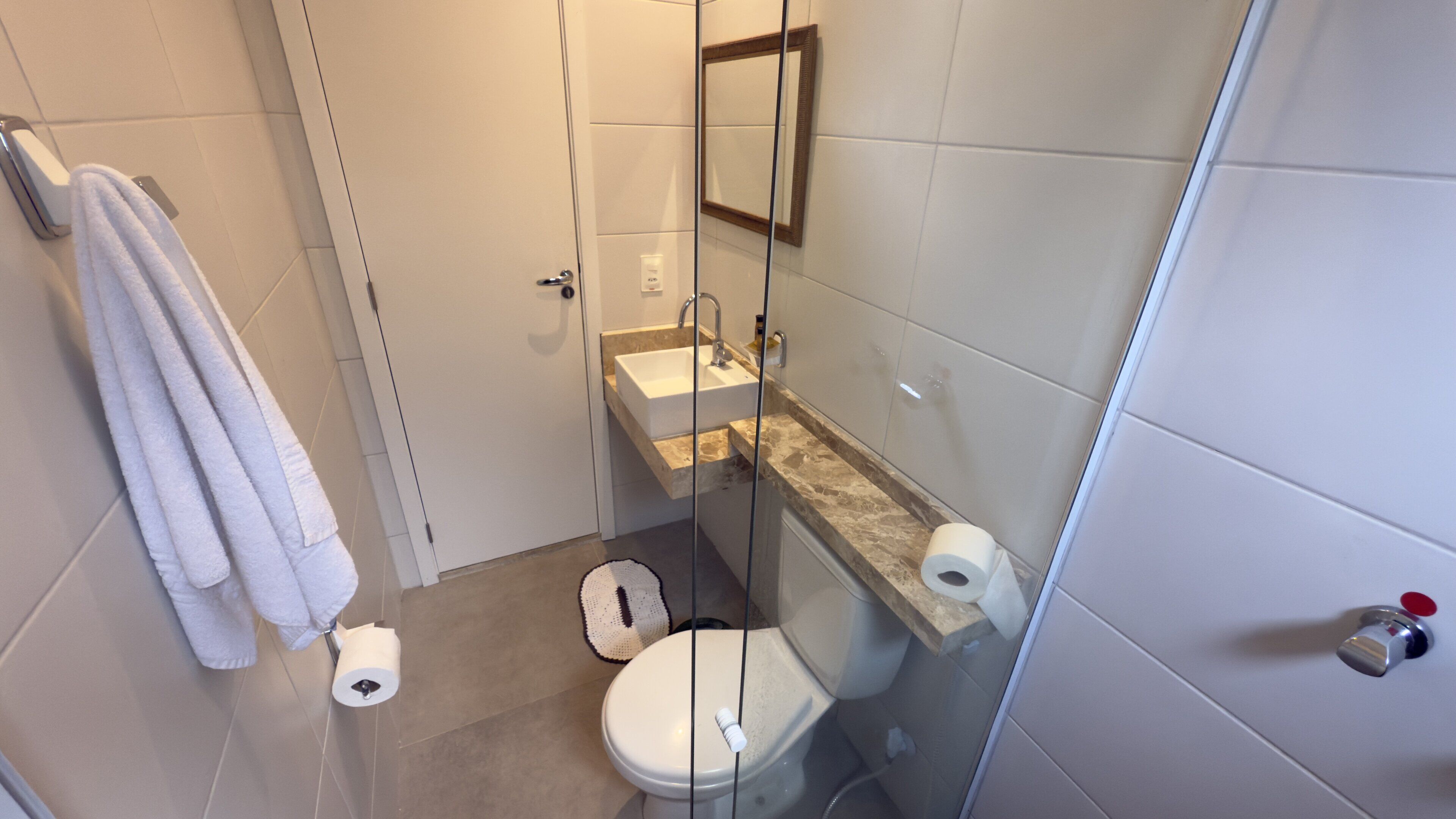Une salle de bain moderne équipée de toilettes, d’un lavabo et d’une douche à parois de verre.