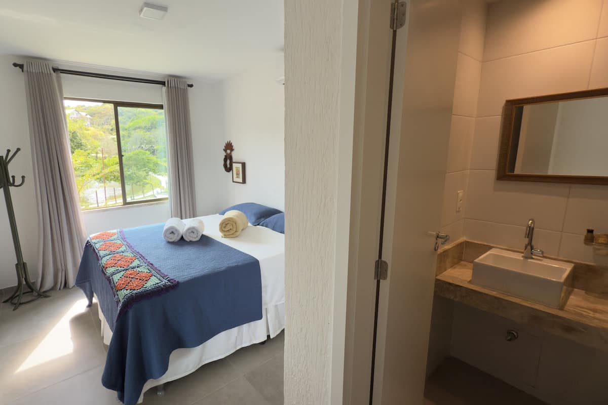 A hotel room with a bed, a bathroom, and a view of the outdoors.