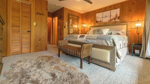 A bedroom with wooden walls, a bed with a headboard, a bench, a fur rug, and a ceiling fan. - SlopeView Chalet:Steps 2 Slopes, Fire Pit, Huge Deck, AC, Pet Friendly, Sleeps 9 (Beech Mountain)