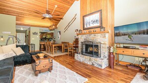 A cozy living room with a stone fireplace, wooden furniture, and a television. - SlopeView Chalet:Steps 2 Slopes, Fire Pit, Huge Deck, AC, Pet Friendly, Sleeps 9 (Beech Mountain)