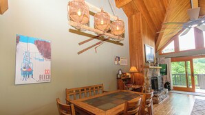 A wooden dining table with chairs, a fireplace, and a ski-themed poster on the wall. - SlopeView Chalet:Steps 2 Slopes, Fire Pit, Huge Deck, AC, Pet Friendly, Sleeps 9 (Beech Mountain)