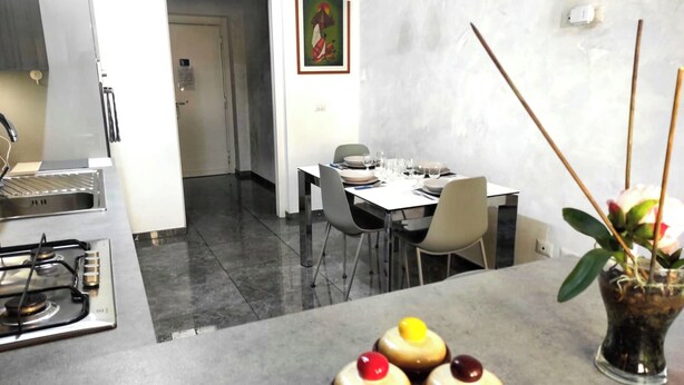 A modern kitchen with a gas stove, a dining area with a table set for four, and a vase with flowers on the counter.