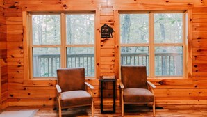 A cabin with two brown chairs facing a large window overlooking a deck. - Cabin, Ensuite Bedrooms, Hot Tub, Firepit, Woods (Campton)
