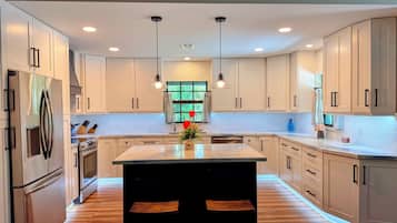 A modern kitchen with white cabinets, stainless steel appliances, and a central island with seating.