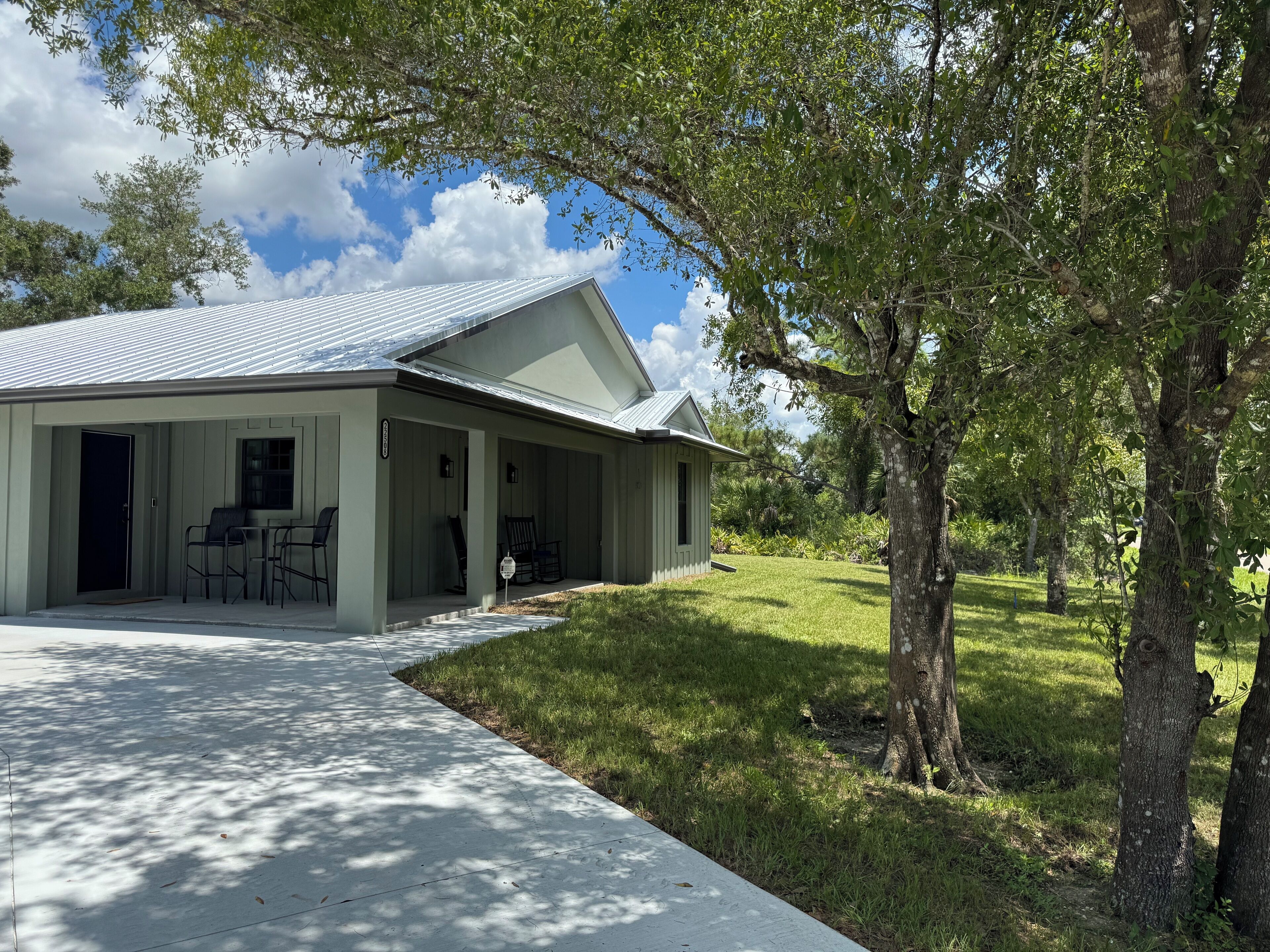 A single-story house with a covered porch, a front door, and a small outdoor seating area.